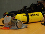 Fluchthaube (vorn) und Pressluftatmer: Beides sind Atemschutzgeräte, erfüllen jedoch völlig andere Aufgaben.